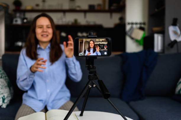 Woman Recording video for blog Woman in shirt Recording video at home for her video blog. Using smartphone live broadcast photos stock pictures, royalty-free photos & images