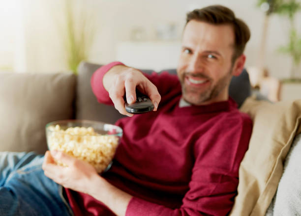 istock Cheerful man watching TV at home 1219344142