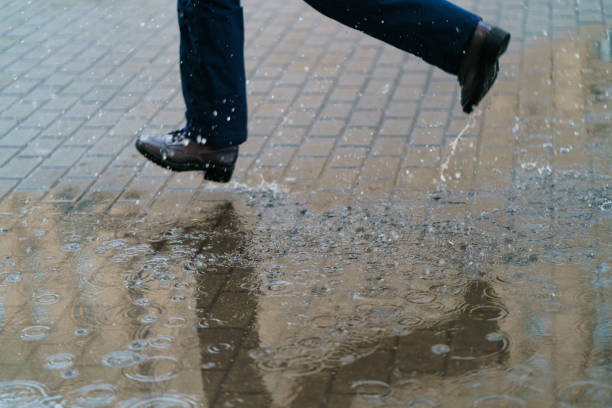 istock Young woman running across the puddles. 1219345097