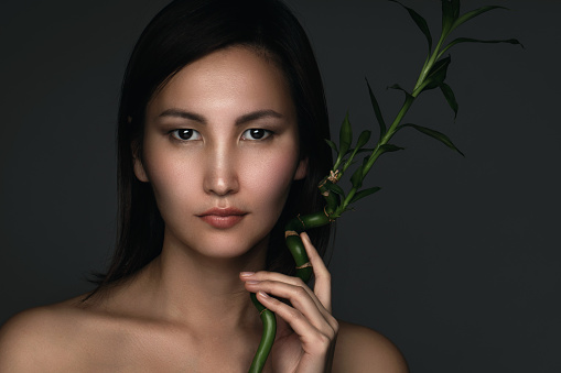 Portrait of young and beautiful asian woman with a bamboo plant in her hands