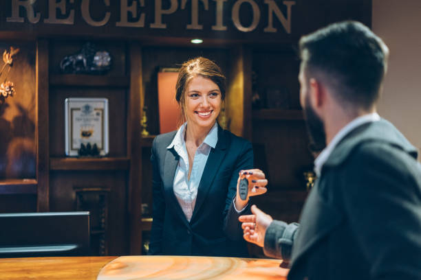 receptionist che dà le chiavi agli ospiti dell'hotel - women customer service representative service standing foto e immagini stock