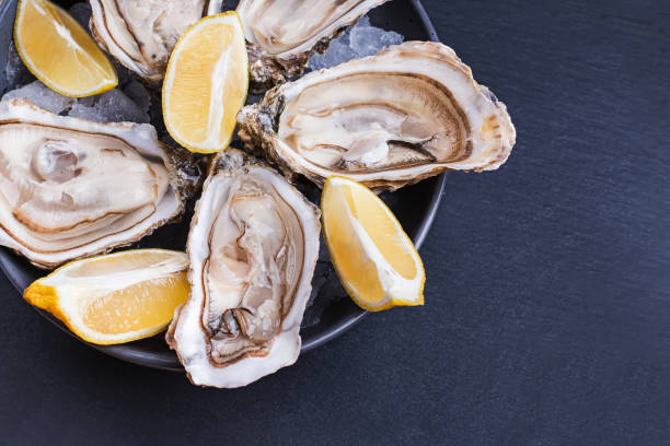 istock Fresh raw opened oysters with ice and lemon slices in a bowl 1219352267