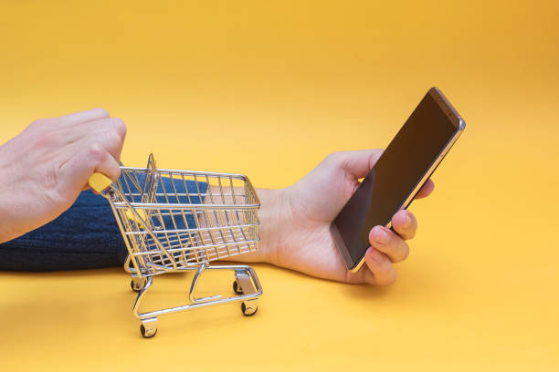 istock Hands holding mini shopping trolley and smartphone. 1219352344