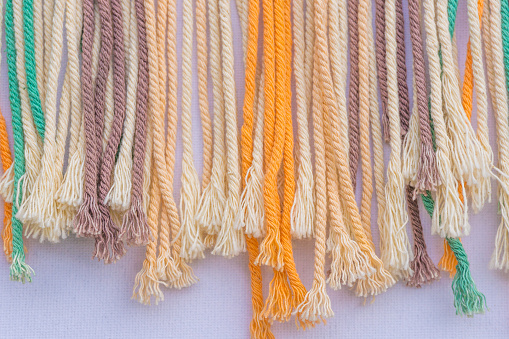 Colourful frayed macrame threads texture for background. Horizontal close up.