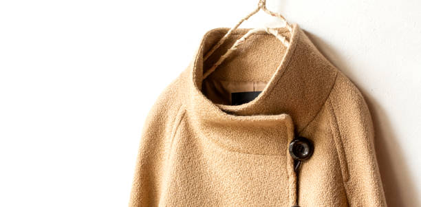 istock beige wool coat hanging on clothes hanger on white background. 1219357276
