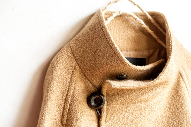 istock beige wool coat hanging on clothes hanger on white background. 1219357304