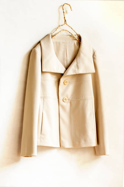 istock beige or white jacket hanging on clothes hanger on white background. 1219358047