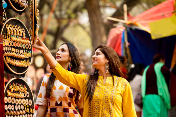Two women shopping for earrings at street market Two beautiful Indian women shopping for earrings at Surajkund Mela fashion bazaar stock pictures, royalty-free photos & images