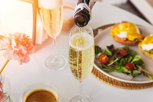 Pouring prosecco sparkling wine in a glass on sunday brunch Pouring prosecco sparkling wine in a glass on sunday brunch with blurred eggs royal on the background. PROSECCO stock pictures, royalty-free photos & images