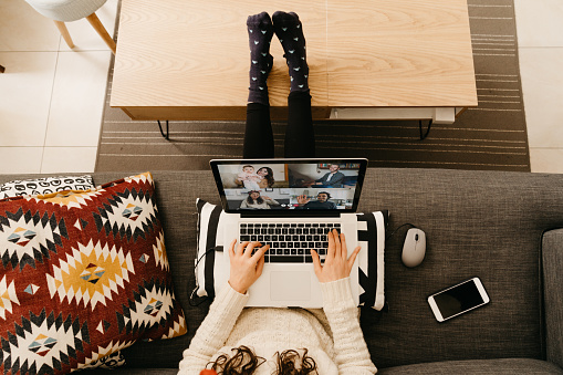 Young woman using a laptop to connect with her friends and relatives during quarantine. She's having a video conference during Coronavirus COVID-19 time.