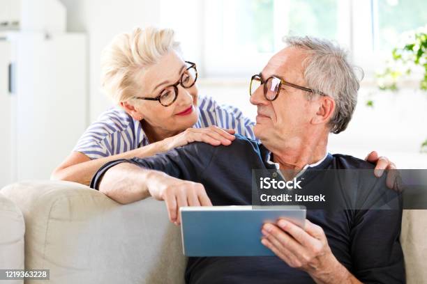 Friendly Senior Couple At Home Stock Photo - Download Image Now - Choosing, Eyeglasses, Couple - Relationship
