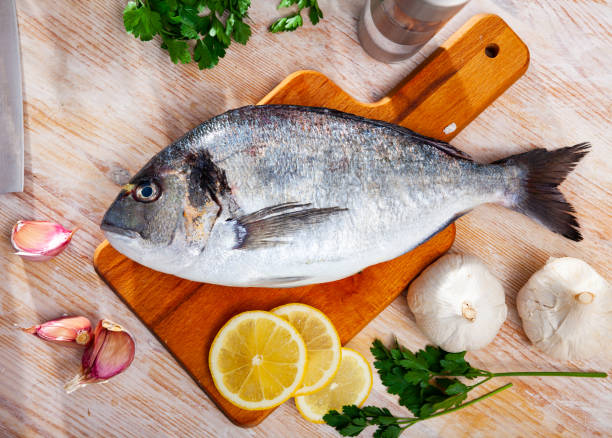 istock Uncooked whole dorado fish with lemon, garlic and greens 1219363464