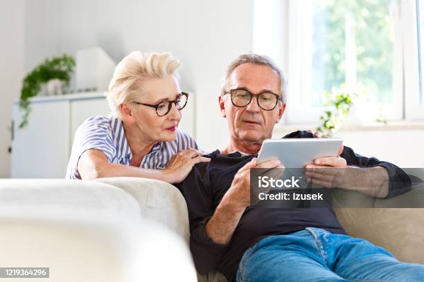 Senior Couple Watching Digital Tablet Together At Home Stock Photo - Download Image Now