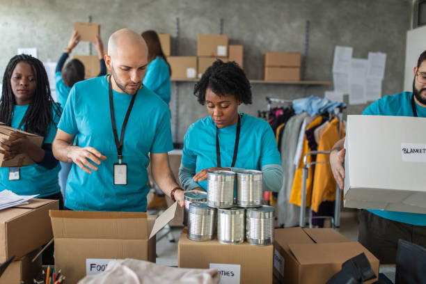 istock Multi-ethnic volunteers packing cardboard boxes with humanitarian aid while working at charitable foundation 1219364453