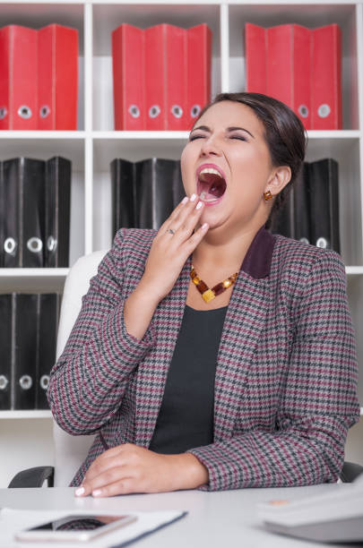 Tired business woman yawning in office. Overwork concept stock photo