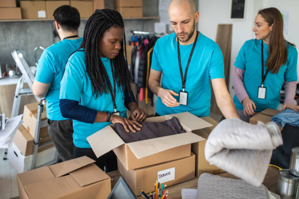 istock Multi-ethnic volunteers packing cardboard boxes with humanitarian aid while working at charitable foundation 1219364953