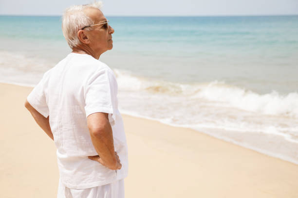 istock Happy senior man walking on the beach 1219365353