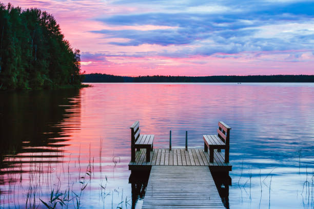 dos sillas de madera en un muelle de madera con vistas a un lago al atardecer - finland lake summer couple fotografías e imágenes de stock