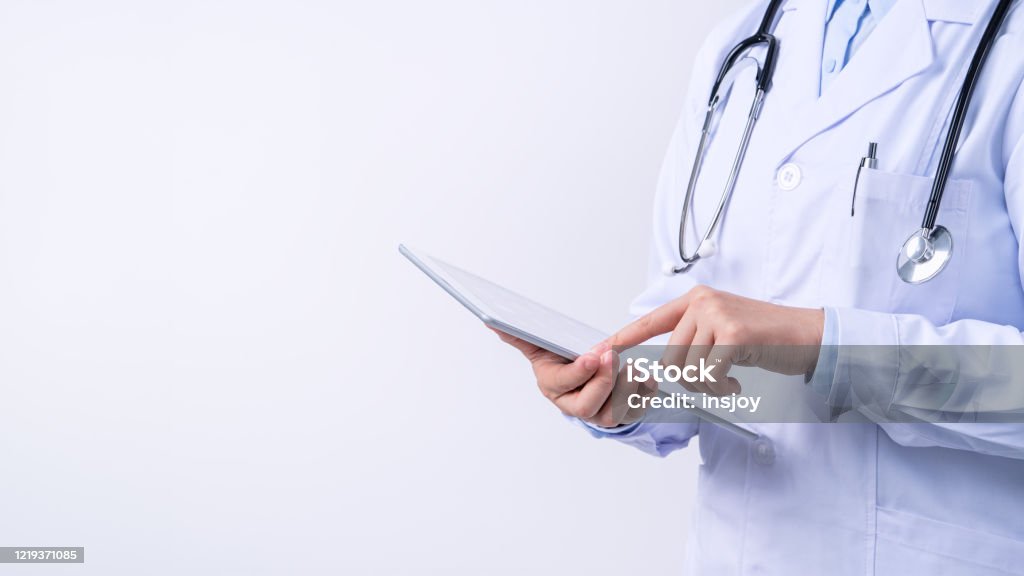 Doctor with stethoscope in white coat holding tablet, showing medical information, diagnosis, isolated on white background. Doctor with stethoscope in white coat holding tablet, showing medical information, diagnosis, isolated on white background, close up, cropped view. Doctor Stock Photo