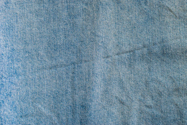 istock Blue Denim Jeans Fabric Textile Material Worn Shabby Faded Folded Texture Surface Background. 1219372488