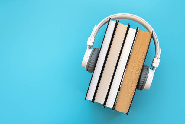 white headphones with stack of books on blue background. audio books or modern education concept - hardcover book audio imagens e fotografias de stock