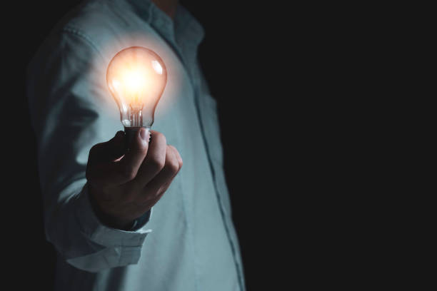 Businessman holding lightbulb which it glowing on black background and copy space .Creativity idea concept.