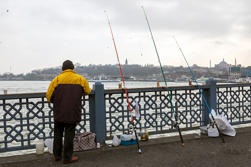 Istanbul, Turkey - December 2019. Fishermen catch fish at Galata Bridge.