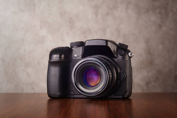 istock Digital mirrorless professional camera on wooden table with concrete wall as a background 1219385669