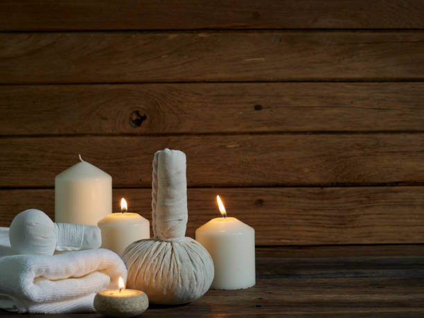 istock Spa herbal compressing ball with alight scented candles on wooden background. 1219387462