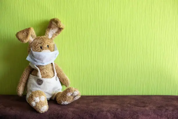 Easter bunny at home in face mask symbolizing lonely Easter 2020. Coronavirus Easter rabbit.