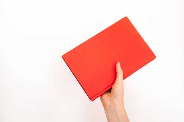 istock Hand holding book in red cover with selective focus on white background and copy space. Concept education, learning and studying 1219389735
