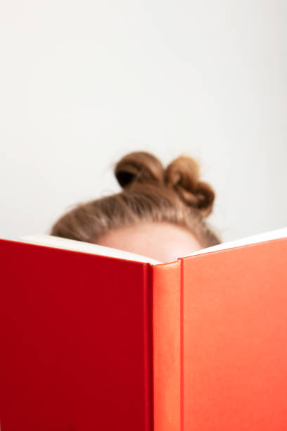 istock Young woman reads book. Selective focus on red book. Concept education, learning and studying at home 1219389935
