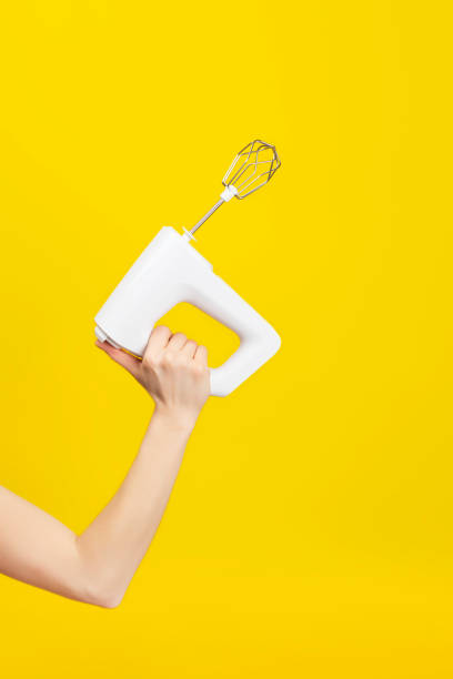 istock White kitchen mixer in female hand isolated on bright yellow background 1219390897