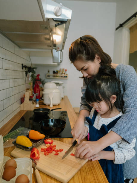 istock Millennial mother preparing breakfast at kitchen with her daugther's helping hand cooking omelet at home. 1219391048