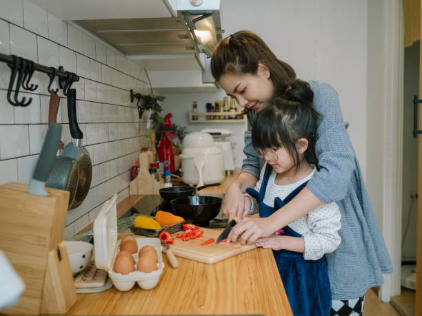 istock Millennial mother preparing breakfast at kitchen with her daugther's helping hand cooking omelet at home. 1219391051
