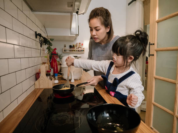 istock Millennial mother preparing breakfast at kitchen with her daugther's helping hand cooking omelet at home. 1219391148
