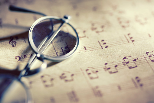 Old grunge sheet music papers with vintage glasses.