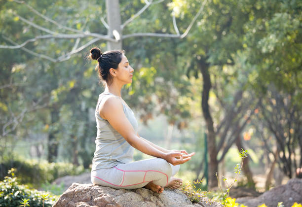 istock Woman practicing yoga in lotus position at park 1219392950