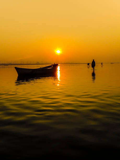 Indian sunrise Allahabad, India- February 09 2013: Beautiful sunrise with lonely man walking at the Ganges river on the main day of the Kumbh Mela festival, in Allahabad, Uttar Pradesh, India. prayagraj photos stock pictures, royalty-free photos & images
