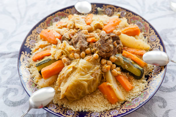Friday Moroccan couscous Top view shot of friday gathering family size delicious couscous plated with stew, vegetables and beef with spoons. Moroccan gastronomy essentials for Ramada and holidays. hari raya family stock pictures, royalty-free photos & images