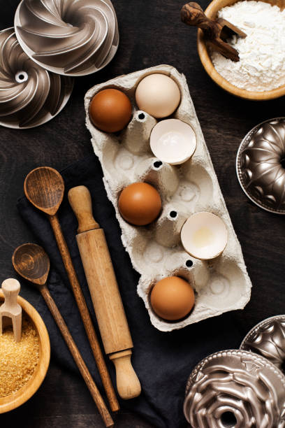istock White and yellow chicken eggs and shells in an old cellulose vintage container with flour, sugar, wooden spoons and a rolling pin on an old dark wooden background. Baking and culinary background. Top view with copy space. 1219394225