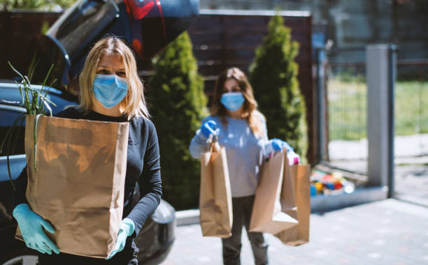 Women buying groceries and back home. Wearing protective mask and gloves stock photo