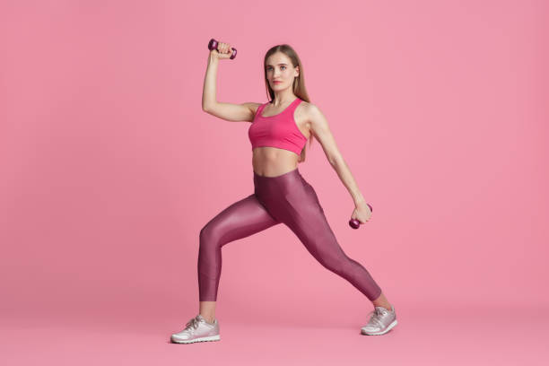 istock Beautiful young female athlete practicing on pink studio background, monochrome portrait 1219394372