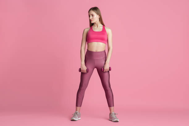istock Beautiful young female athlete practicing on pink studio background, monochrome portrait 1219394407