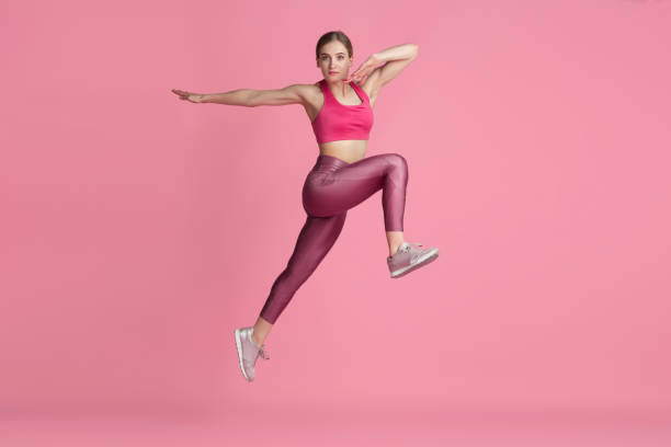 istock Beautiful young female athlete practicing on pink studio background, monochrome portrait 1219394444