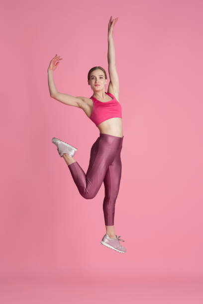istock Beautiful young female athlete practicing on pink studio background, monochrome portrait 1219394457