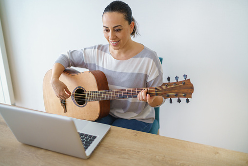 Young musician working at home with her guitar.
