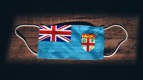 Fiji National Flag at medical, surgical, protection mask on black wooden background. Coronavirus Covid"u201319, Prevent infection, illness or flu. State of Emergency, Lockdown... Fiji National Flag at medical, surgical, protection mask on black wooden background. Coronavirus Covid"u201319, Prevent infection, illness or flu. State of Emergency, Lockdown... suva photos stock pictures, royalty-free photos & images