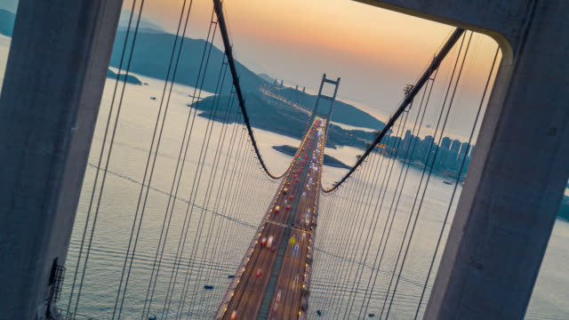 Hyperlapse or Dronelapse Aerial view of Traffic of car at Tsing ma bridge in Tsing yi area of Hong Kong at sunset. Day to night timelapse