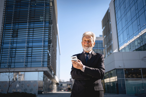 Portrait of smiling senior businessman in front of the modern building.